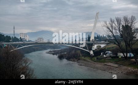 Millenium-Brücke über den Fluss Moraca in Podgorica, Montenegro. Blick auf Podgorica Stadt mit dem Fluss Moraca in Montenegro. Abend, Winter, bewölkt Stockfoto