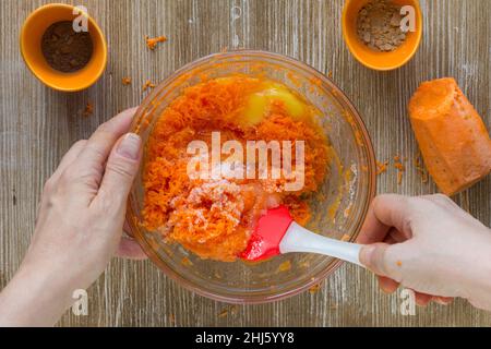 Frau Hände Mischen Teig für Karottenkuchen auf Holz Hintergrund Stockfoto