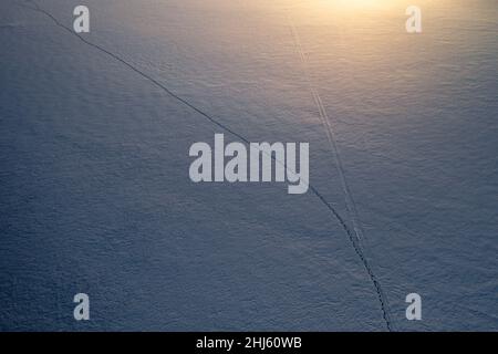 Fußspuren im Schnee auf gefrorenem See im Winter Stockfoto