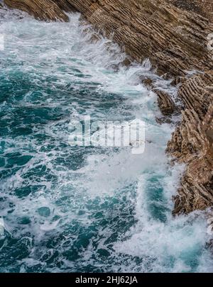 Dramatischer Meereshintergrund. Felsküste der Adria. Weiße, schäumende Wellen schlagen gegen das steinerne Ufer. Panorama der Küste. Luftaufnahme von oben. Adria Stockfoto