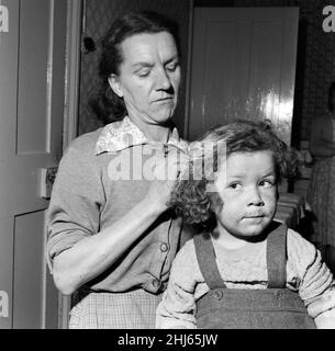 Frau Gladys Batt versucht, ihre vierjährige Tochter Georgina von Farbe zu reinigen. 16th. Oktober 1958. Stockfoto