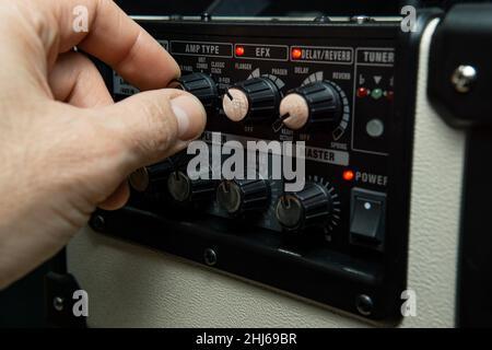 Nahaufnahme der Hand eines Mannes, der die Verstärkerknöpfe justiert Stockfoto