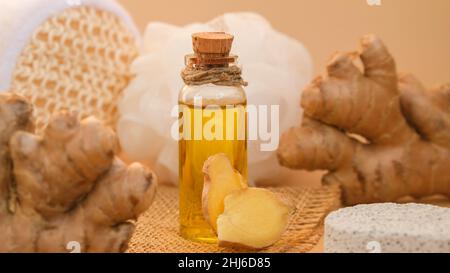 Glasflasche mit ätherischem Ingweröl, Ingwerwurzel auf beigem Hintergrund. Spa-Konzept. Massage Bio-Öl natürliche Kosmetik-Inhaltsstoffe für die Hautpflege Stockfoto