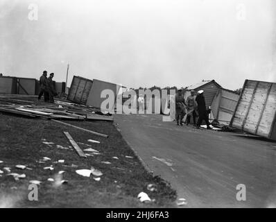 Sturmschaden. Ein Paar klammert sich verzweifelt an ihre umgekehrte Strandhütte in Littlehampton, um zu verhindern, dass sie weggeblasen wird. Littlehampton, West Sussex. 29th. Juli 1956. Stockfoto