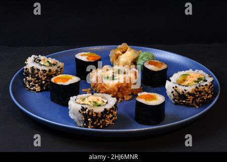 Japanisches Sushi auf einem Porzellanteller auf schwarzem Hintergrund Stockfoto