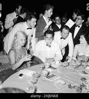 1956 Venice Film Festival, Freitag, 31st. August 1956. Unser Bild Zeigt ... Die französische Schauspielerin Helene Remy (links) und die italienische Schauspielerin Gina Lollobrigida (rechts, ebenfalls Milko Skofic, Ehemann von Gina, und Bernard McElwaine, Bildjournalist am Sonntag (stehend, im Gespräch mit Gina). Stockfoto