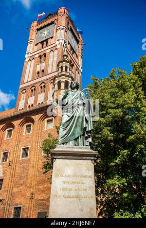 Torun, Polen - 11. August 2021. Denkmal von Nicolaus Copernicus eingeschrieben Thorunensis. Der alte Rathausturm im Hintergrund. Stockfoto