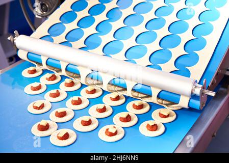 Maschinenförderer für die Zubereitung von mit Käse und Tomatenmark gefüllten Backwaren Stockfoto