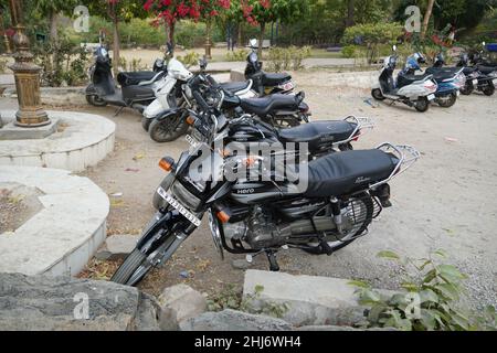 Viele Motorräder und Motorroller sind vor einem Garten geparkt. Öffentlicher Bereich. Niemand anwesend. Straßenansicht von vielen Motorrädern am Straßenrand. - Mumbai Indi Stockfoto