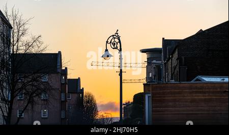 Leith, Edinburgh, Schottland, Großbritannien, 27th. Januar 2022. UK Wetter: sonnenaufgang über Gebäuden an der Küste in Leith mit einem altmodischen Lampenpfosten Stockfoto