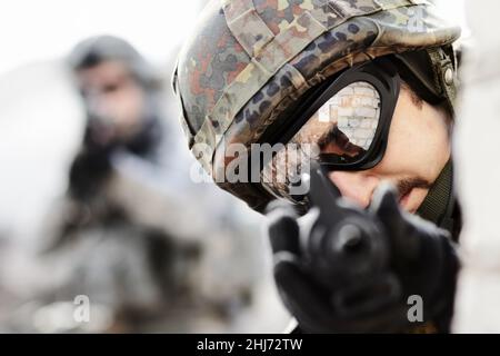 Shooter mit Adleraugen. Nahaufnahme eines Scharfschützen mit Waffe, die auf die Kamera gerichtet ist, und eines Soldaten im Hintergrund mit Kopierraum. Stockfoto