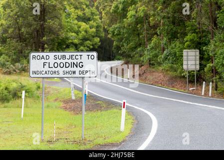 Ein Hochwasserwarnschild auf einer tief liegenden Straße im regionalen Norden von New South Wales, Australien, die das Ausmaß des Wassers über der Straße zeigt Stockfoto