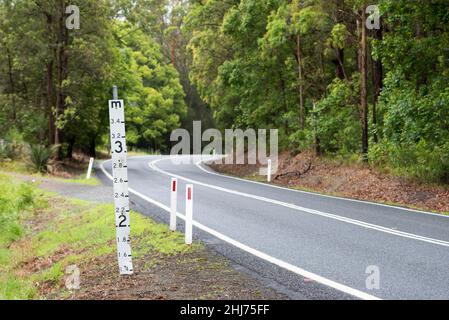 Ein Hochwassermeßschild auf einer tief liegenden Straße im regionalen Norden von New South Wales, Australien, das die Wassermenge über der Straße zeigt Stockfoto