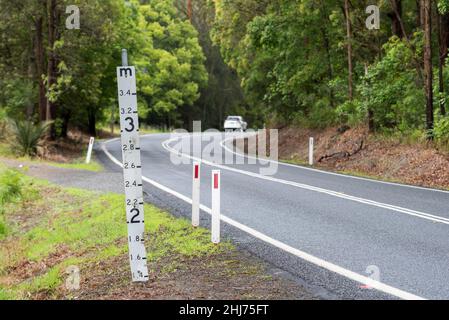 Ein Hochwassermeßschild auf einer tief liegenden Straße im regionalen Norden von New South Wales, Australien, das die Wassermenge über der Straße zeigt Stockfoto