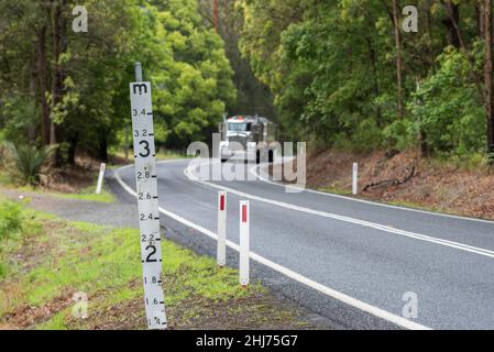 Ein Hochwassermeßschild auf einer tief liegenden Straße im regionalen Norden von New South Wales, Australien, das die Wassermenge über der Straße zeigt Stockfoto