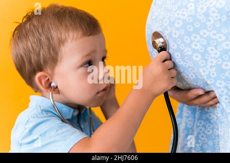 Mutterschaft, heißen Sommer - croped Portrait schwanger Mutter unkenntlich Frau blau Kleid kleinen Jungen Sohn Geschwister behandeln schwanger Mutter Rollenspiel Stockfoto