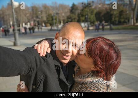 Ein älteres kaukasisches Paar, das ein Foto von sich selbst gemacht hat, das sich mit einem Mobiltelefon auf der Straße küsst Stockfoto