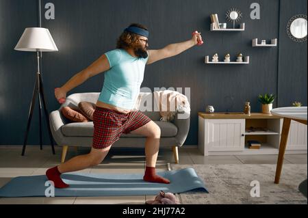 Lustiger Mann beim morgendlichen Training mit Hanteln Stockfoto