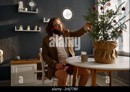 Freiberuflicher Geschäftsmann schmücken Tannenbaum mit Kugeln Stockfoto