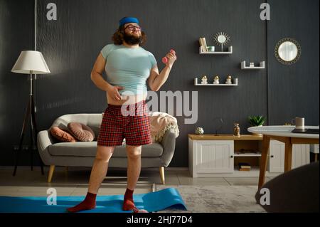 Lustiger Mann beim morgendlichen Training mit Hanteln Stockfoto