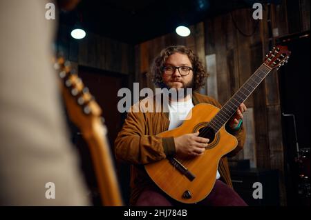 Musiklehrer, der die Eigenschaften des Gitarrenspiels erklärt Stockfoto