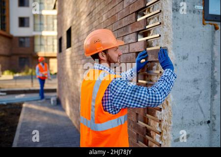 Arbeiter Verkleidung Stein für externe Wand Erwärmung Stockfoto