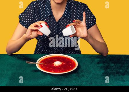 Kreatives Porträt einer jungen Frau, die Kleidung im Vintage-Stil trägt und ukrainischen Borschtsch isst. Interieur im Retro-Stil. Food Pop Art Fotografie. Stockfoto