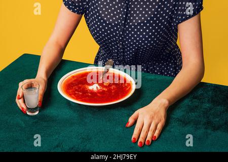 Kreatives Porträt einer jungen Frau, die Kleidung im Vintage-Stil trägt und ukrainischen Borschtsch isst. Interieur im Retro-Stil. Food Pop Art Fotografie. Stockfoto