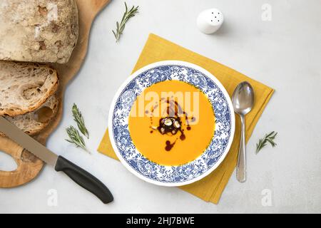 Frische vegane Kürbiscremesuppe auf dem Teller mit Haselnüssen und Kürbisöl, serviert mit frischem Brot. Flacher Lay, fertig zum Essen Butternut Squash Suppe auf n Stockfoto