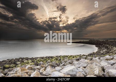 Sonnenuntergang über der Morecambe Bay mit der Küstenlinie, die sich in die Ferne schweigt Stockfoto