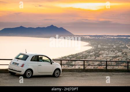 Terracina, Italien. Weiße Farbe Fiat 500 Facelift 2016 Auto Geparkt Auf Hintergrund Circeo Promontory Und Tyrrhenisches Meer Bei Sonnenuntergang Oder Sonnenaufgang Zeit Stockfoto