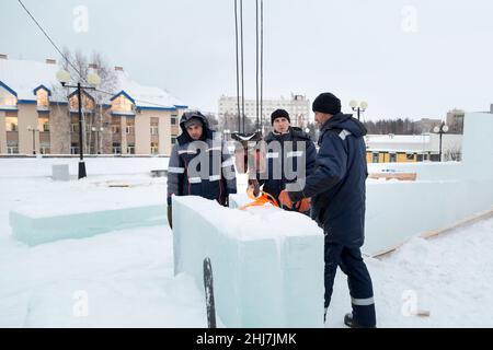 Drei Arbeiter bedecken den Rahmen einer Holzrutsche mit Eisplatten Stockfoto