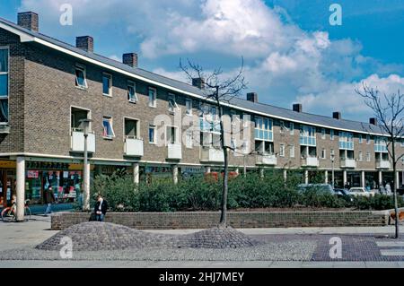 Neue Geschäfte und Wohnungen (Maisonetten) oben an der Tilgate Parade, Ashdown Drive im Tilgate-Viertel von Crawley ‘New Town’, West Sussex, England, Großbritannien im Jahr 1966. Das Viertel, südlich des Stadtzentrums, war eines von 14 Vororten, die zur Schaffung der ‘neuen Stadt’ nach dem Krieg entwickelt wurden. Die Parade mit Backsteinfront hat eine sanft geschwungene Form. Nach dem Zweiten Weltkrieg wurden viele Menschen und Arbeitsplätze in neue Städte im Südosten Englands verlegt, um die Bewohner der armen oder bombardierten Londoner Wohnungen umzusiedeln, und Crawley war die einzige von ihnen. Dieses Bild stammt aus einer alten Amateur-Farbtransparenz – einem Vintage-Foto aus dem Jahr 1960s. Stockfoto