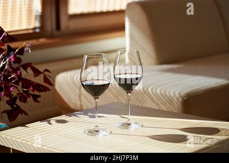 Zwei Gläser Rotwein auf einem Tisch in einer sonnigen Wohnung Stockfoto