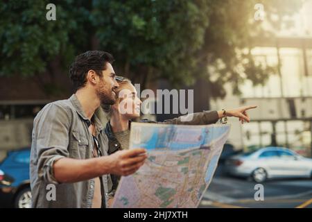 Lassen Sie Neugier den Weg gehen. Aufnahme eines jungen Paares auf einer Karte während der Erkundung der Stadt. Stockfoto