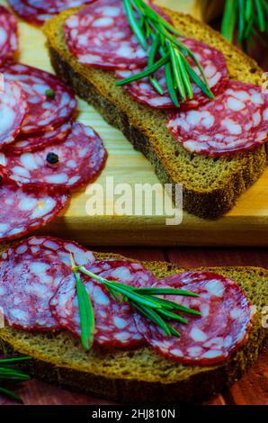 Würstchen-Sandwiches auf einem Holzbrett und Gewürze in der Nähe Stockfoto