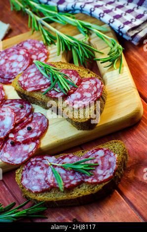 Würstchen-Sandwiches auf einem Holzbrett und Gewürze in der Nähe Stockfoto