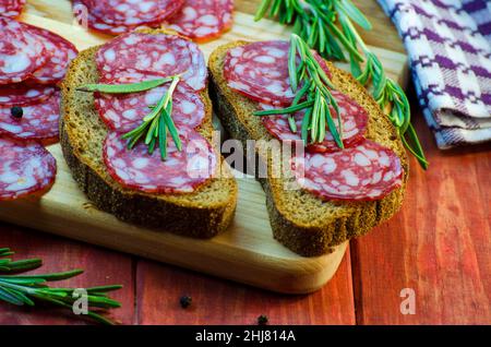 Würstchen-Sandwiches auf einem Holzbrett und Gewürze in der Nähe Stockfoto