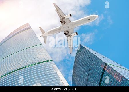 Das Flugzeug fliegt im Himmel über Wolkenkratzern in der Stadt Stockfoto