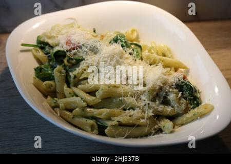 Scampi und Spinaci Pasta mit Penne. Teller mit köstlichen Pasta italienischen Stil. Voller Kohlenhydrate und Fett, aber super lecker! Nahaufnahme des Farbbildes. Stockfoto