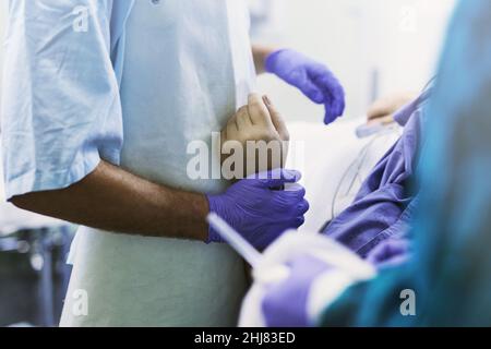 Sie sind jetzt in sicheren Händen. Abgeschnittene Aufnahme eines Arztes, der einen Patienten während eines medizinischen Eingriffs am Handgelenk hält. Stockfoto