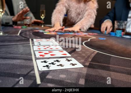 Fünf Karten auf dem Spieltisch im Casino auf dem Hintergrund von Menschen, die Poker spielen Stockfoto