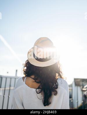 Nahaufnahme einer nicht erkennbaren jungen Frau mit Hut, die sich von hinten aus der Terrasse lehnt Stockfoto