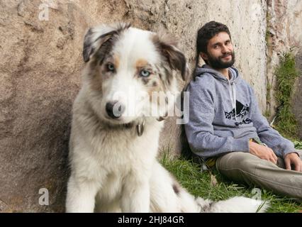 Hispanischer Mann und brauner Border Collie lieben sich im Freien Stockfoto