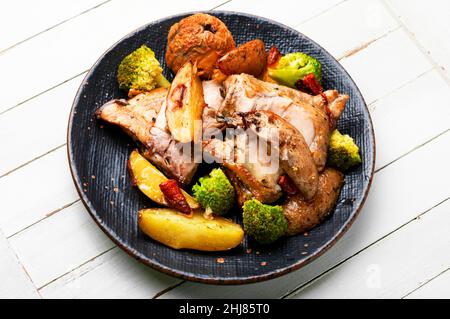 Gegrilltes Hähnchenfleisch mit Gemüse und Apfel. Geschmorte Hähnchenschenkel auf weißem Hintergrund Stockfoto