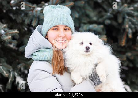 Glückliches Teenager-Mädchen, das im Winter mit ihrem Hund auf dem Schnee spielt. Schnee-Spiele. Winterurlaub. Stockfoto