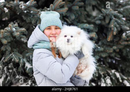 Glückliches Teenager-Mädchen, das im Winter mit ihrem Hund auf dem Schnee spielt. Schnee-Spiele. Winterurlaub. Stockfoto