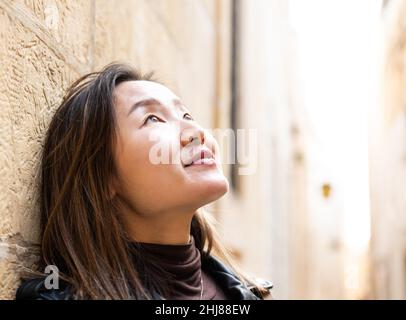 Porträt eines 29-jährigen asiatisch-amerikanischen Mädchens, das mit Gegenlicht aufschaut, Mdina, Malta Stockfoto