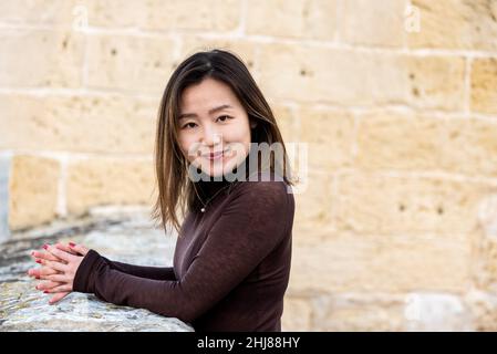 Porträt eines 29-jährigen asiatisch-amerikanischen Mädchens, das auf einer Festung steht, die Hände gefaltet Stockfoto