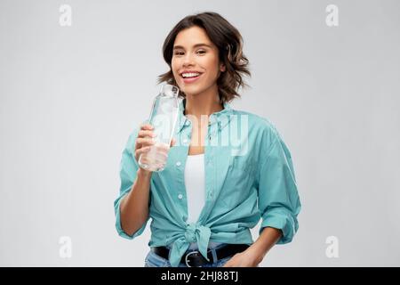 Lächelnde Frau, die Wasser aus der Glasflasche trinkt Stockfoto